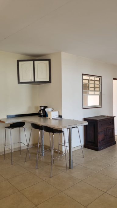 Moderne keuken met een bar en hoge stoelen, lichte muren en een houten kast.