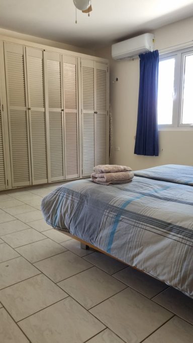 Slaapkamer met een bed, een kast, en een raam met een blauwe gordijn.